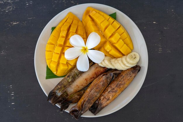 Mango amarillo de postre de estilo tailandés con arroz pegajoso de plátano en hojas de palma Mango amarillo y arroz pegajoso es comida tradicional popular de Tailandia Primer plano