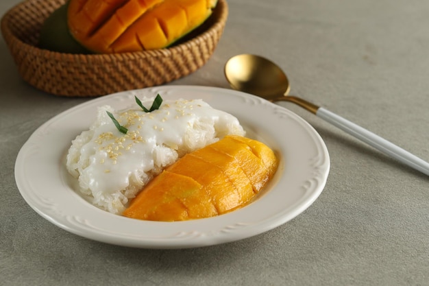 El mango con arroz pegajoso es un postre típico tailandés elaborado con arroz glutinoso y salsa de leche de coco.