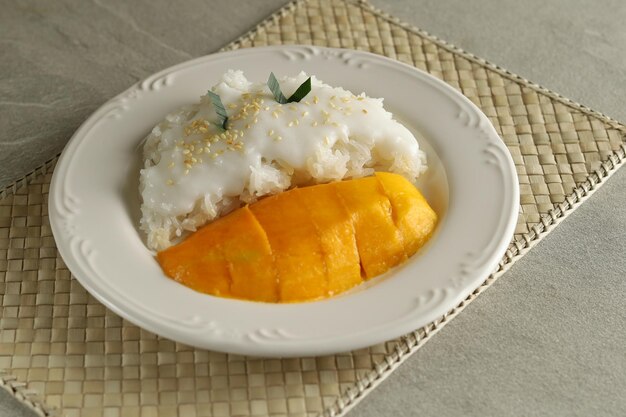 El mango con arroz pegajoso es un postre típico tailandés elaborado con arroz glutinoso y salsa de leche de coco.