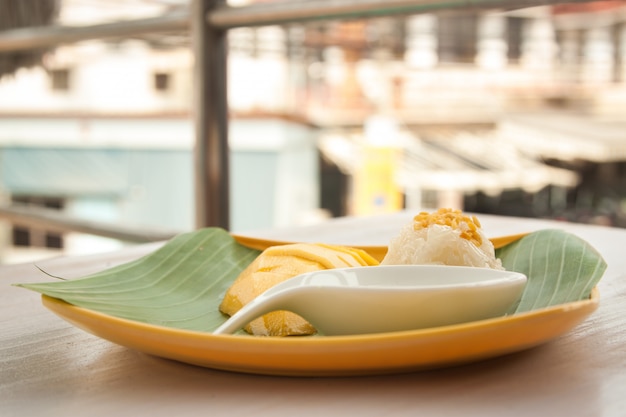 Mango y arroz pegajoso con leche de coco en el plato amarillo