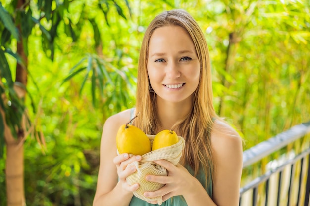 Mango em um saco reutilizável em mãos femininas conceito de desperdício zero conceito livre de plástico dieta de alimentação limpa saudável e desintoxicação Frutas de verão