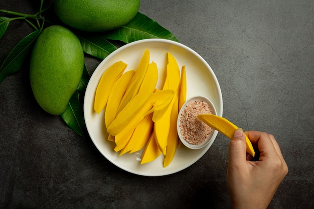 Mango en escabeche sobre superficie de madera oscura.