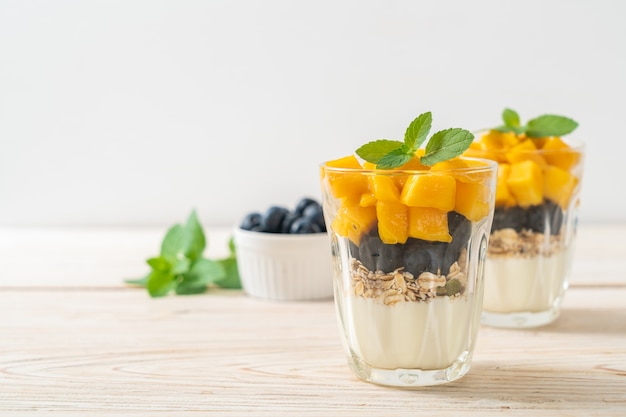 mango fresco casero y arándanos frescos con yogur y granola - estilo de comida saludable
