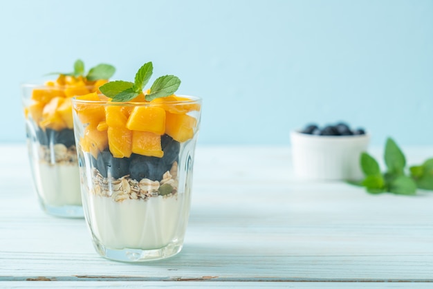 mango fresco casero y arándanos frescos con yogur y granola - estilo de comida saludable