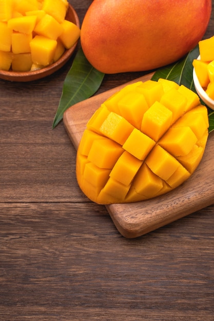 Mango fresco - Cubos de mango picado jugosos sobre tabla de cortar de madera y fondo de madera rústica