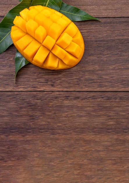 Mango fresco hermosa fruta picada con hojas verdes sobre fondo de madera oscura Concepto de diseño de frutas tropicales Plano Vista superior Espacio de copia