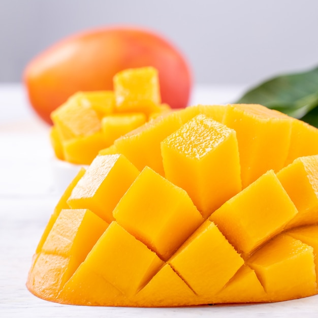 Mango fresco, hermosa fruta picada con hojas verdes sobre fondo de mesa de madera brillante