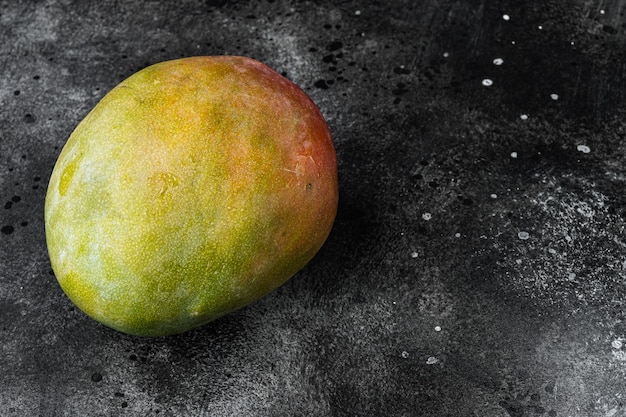 Mango ganzer Fruchtsatz, auf schwarzem dunklem Steintischhintergrund, mit Kopienraum für Text