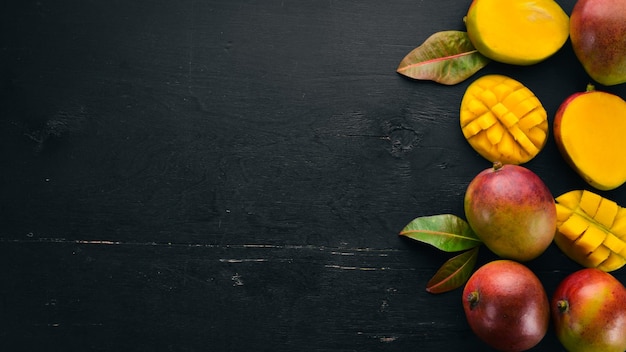 Mango con hojas sobre un fondo de madera negra Frutas tropicales Vista superior espacio libre para su texto