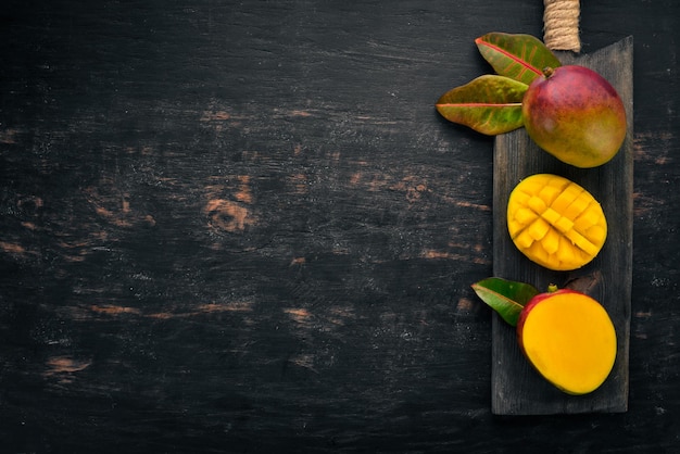 Mango con hojas sobre un fondo de madera negra Frutas tropicales Vista superior espacio libre para su texto