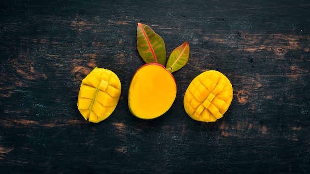 Mango con hojas sobre un fondo de madera negra frutas tropicales vista superior espacio libre para su texto