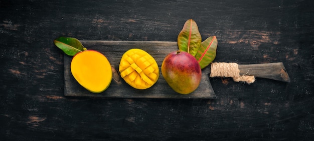 Mango con hojas sobre un fondo de madera negra Frutas tropicales Vista superior espacio libre para su texto