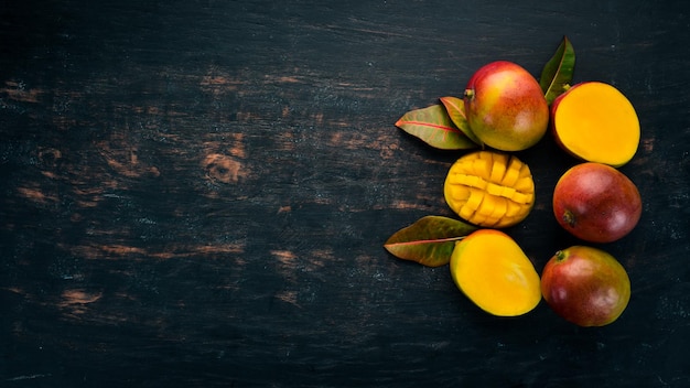 Mango con hojas sobre un fondo de madera negra Frutas tropicales Vista superior espacio libre para su texto