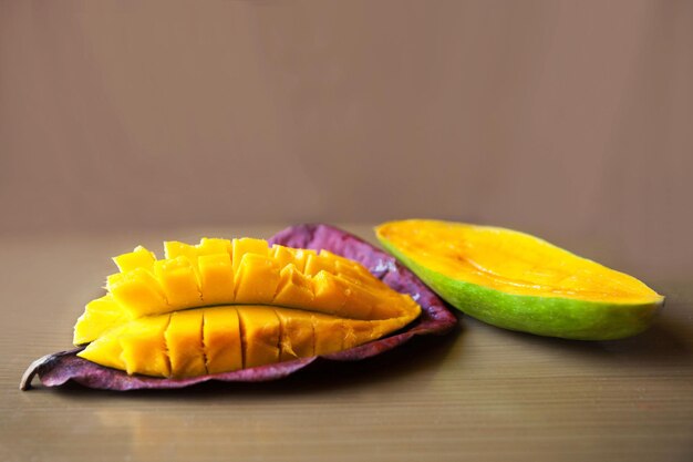 Mango in Scheiben geschnitten auf einem Blatt auf beigem Hintergrund