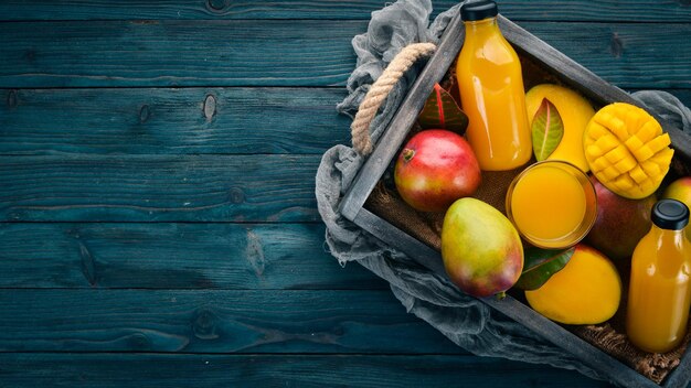 Mango y jugo en una caja de madera Sobre un fondo de madera Frutas tropicales Vista superior Espacio de copia libre