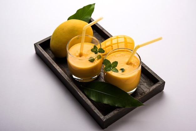 Mango Lassi oder Joghurt, indisches beliebtes Sommergetränk serviert im Glas mit ganzen Alphonso Aam Früchten, selektiver Fokus