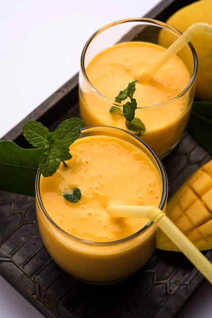 Mango Lassi oder Joghurt, indisches beliebtes Sommergetränk serviert im Glas mit ganzen Alphonso Aam Früchten, selektiver Fokus