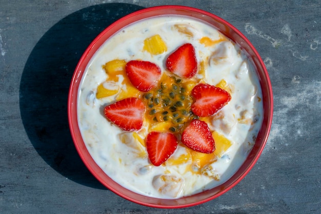 Mango, maracuyá, fresa roja y yogur brulee. Postre de frutas en el desayuno con cuñas de mangos y fresas perfectamente maduros en temporada, cubiertos de pulpa de maracuyá fresca, cerrar