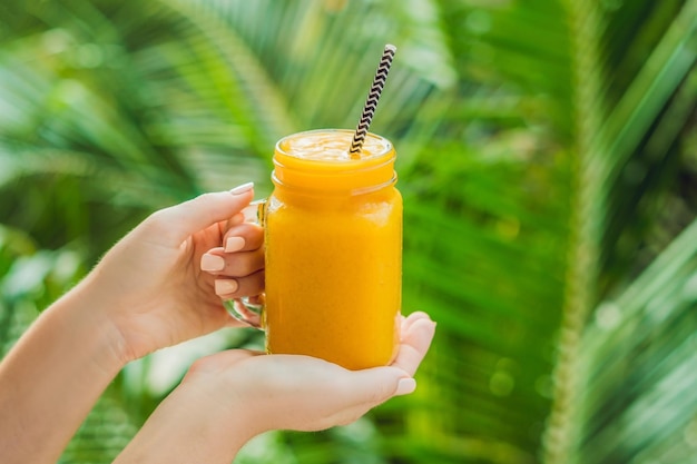 Mango-Smoothie in einem Glas Einmachglas und Mango auf grünem Hintergrund. Mango-Shake. Konzept mit tropischen Früchten