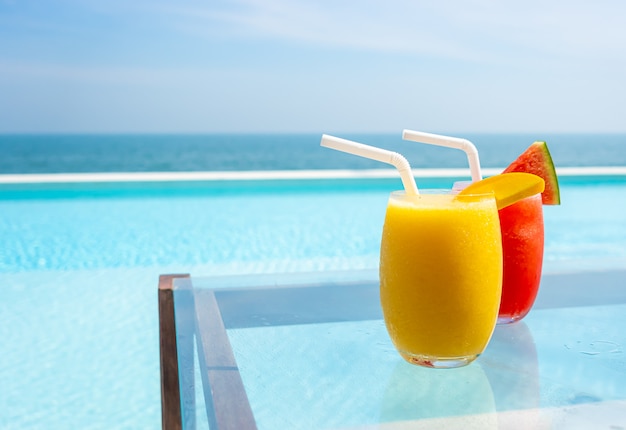 Mango-Smoothie und Wassermelonen-Smoothie mit Swimmingpool und Meeresstrand