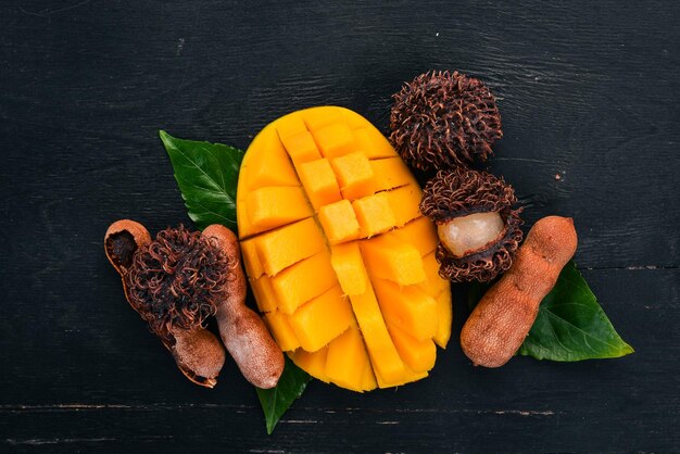Mango-Tamarinde und Rambutan Frische tropische Früchte auf einem hölzernen Hintergrund Ansicht von oben Kopieren Sie Platz