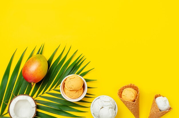 Mango- und Kokoseis mit Palmblatt auf gelbem Hintergrund. Flach legen, Platz kopieren.