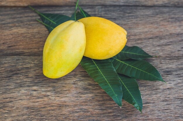 Mango und Mangoblätter auf einem alten Holztisch