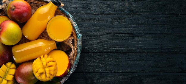 Mango und Saft in einer Holzkiste Auf einem hölzernen Hintergrund Tropische Früchte Draufsicht Kostenloser Kopierbereich