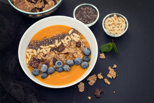 Mangopüree mit Müsli, Chia und Beeren in einer weißen Schüssel