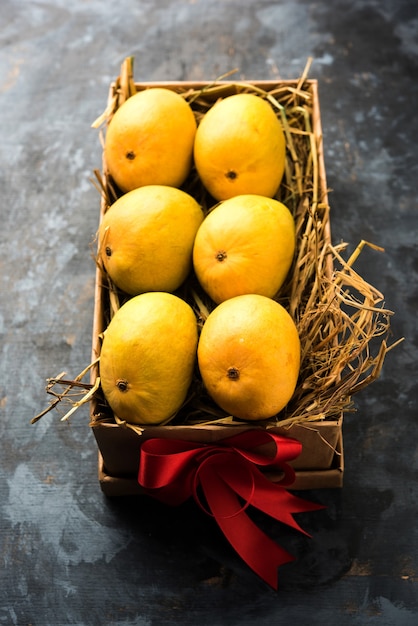 Mangos Alfonso en una caja de regalo sobre hierba y atados con cinta roja, enfoque selectivo