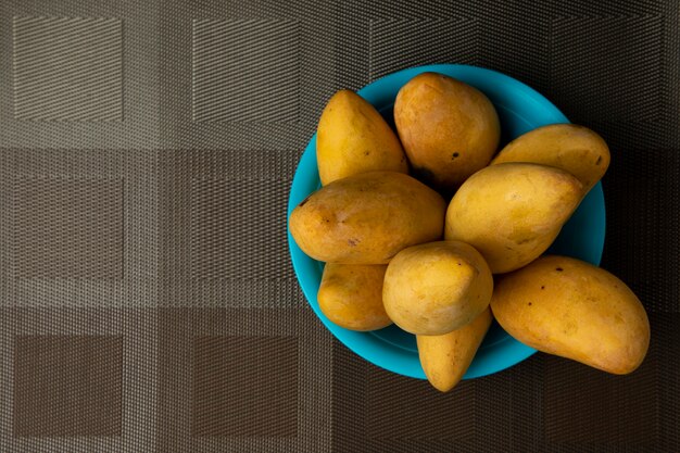 Foto mangos en una placa azul sobre un mantel marrón