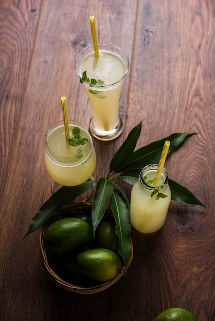 Mangosaft ODER Aam Panna oder Panha in einem transparenten Glas mit ganzen grünen Früchten, selektiver Fokus