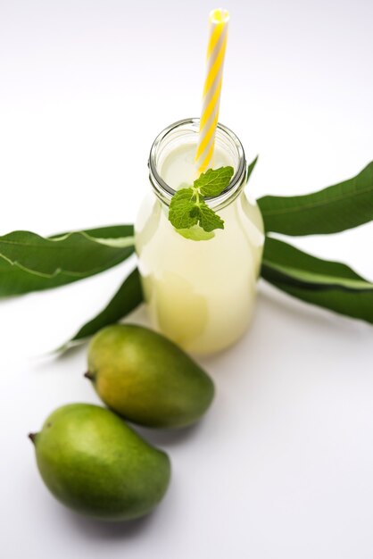 Mangosaft ODER Aam Panna oder Panha in einem transparenten Glas mit ganzen grünen Früchten, selektiver Fokus