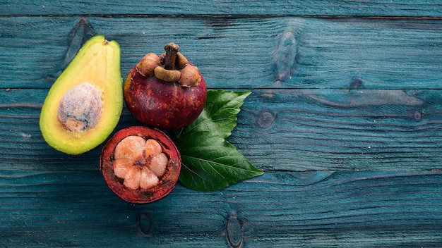 Mangostán y aguacate Frutas tropicales frescas Sobre un fondo de madera Vista superior Espacio de copia