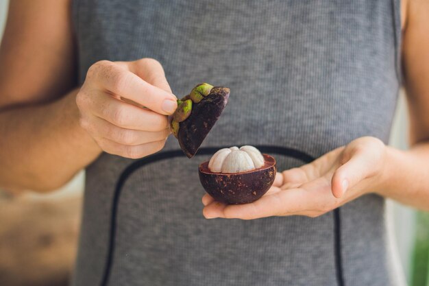 Mangostán en la mano del granjero sostenga la fruta tropical.