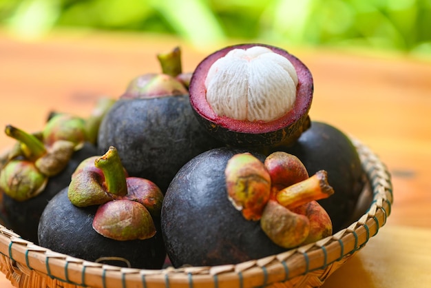 Foto mangosteen em cesta e fundo de madeira mangosteen fresco maduro descascado da árvore em frutas tropicais na tailândia no verão