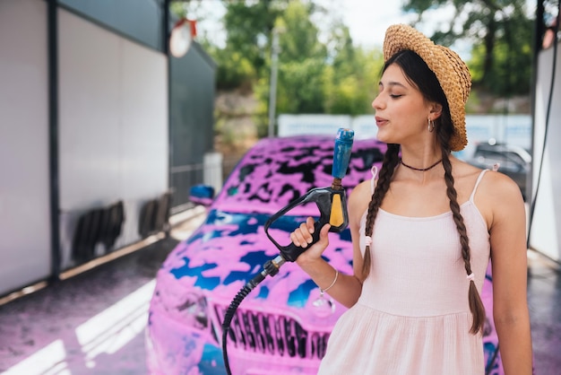 Mangueira jovem fica na frente de um carro coberto de espuma rosa