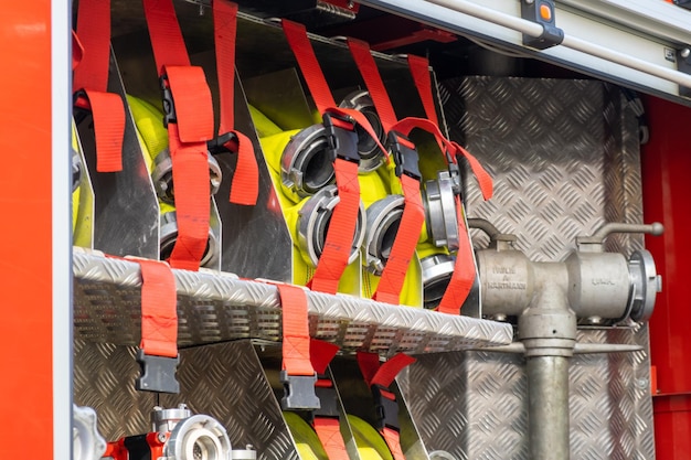 Mangueras enrolladas amarillas sujetas en celdas por cinturones con abrazaderas en cuerpo de metal de camión de bomberos abierto en contempo...