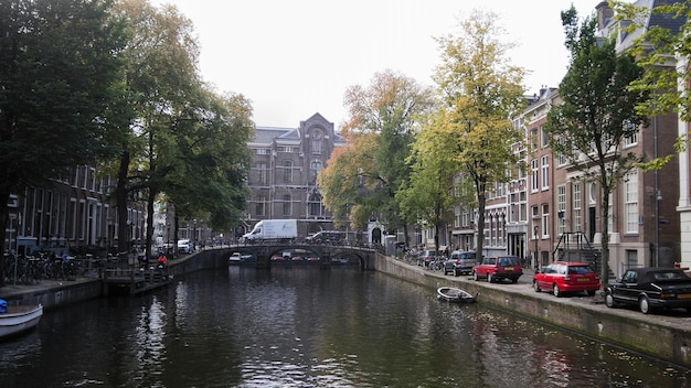 Manhã de Amsterdã no centro da cidade - rua com bicicletas e carros no canal, outono, Holanda, grande angular