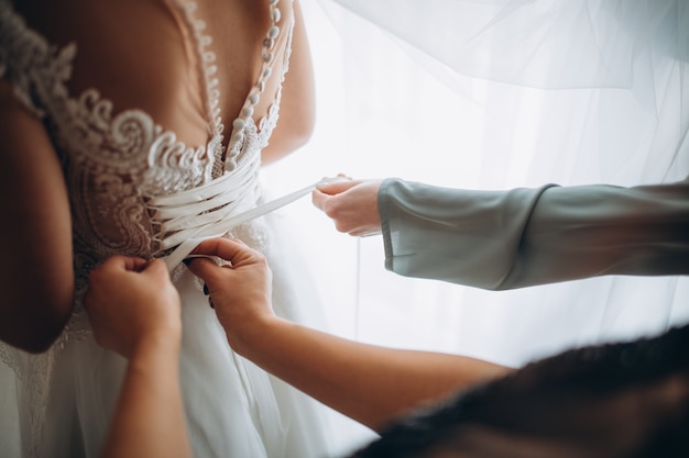 Manhã de casamento. vista lateral da noiva em vestido de noiva. damas de honra preparando a noiva para o dia do casamento.