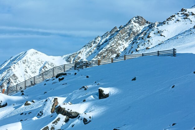 Manhã de inverno vista para a montanha com cerca de madeira na colina (Tirol, Áustria).