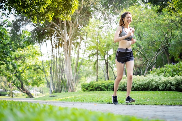 Manhã de jovem esporte asiático mulher correndo ao ar livre no parque natural