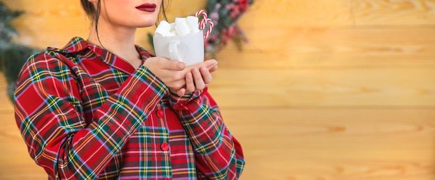 Manhã de natal, mulher de pijama com uma xícara de chocolate quente com marshmallows. foco seletivo.