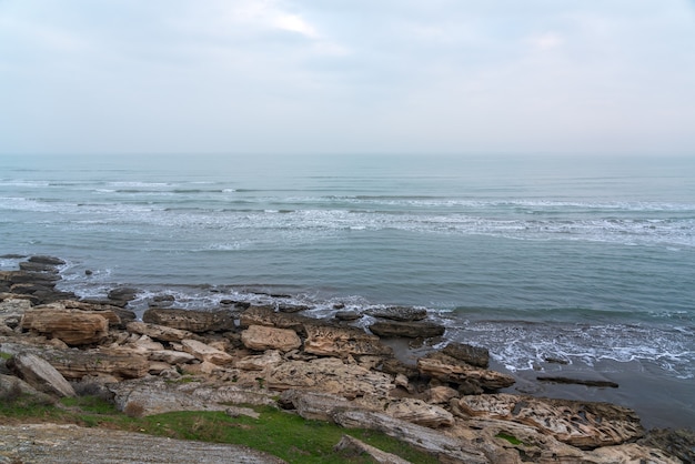 Manhã de nevoeiro na costa rochosa do mar