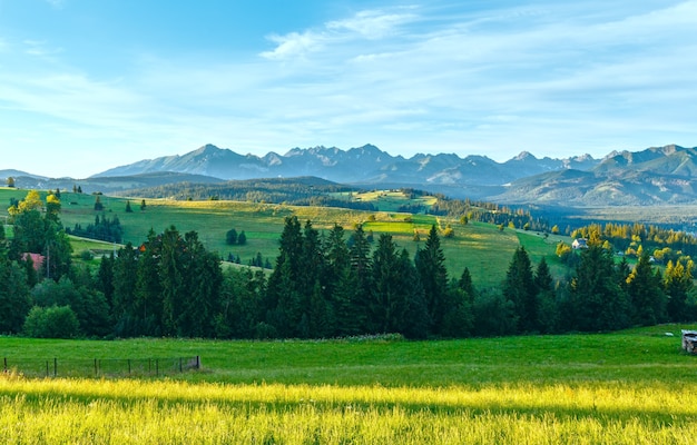 Manhã de verão nos arredores da aldeia nas montanhas e a cordilheira tatra atrás