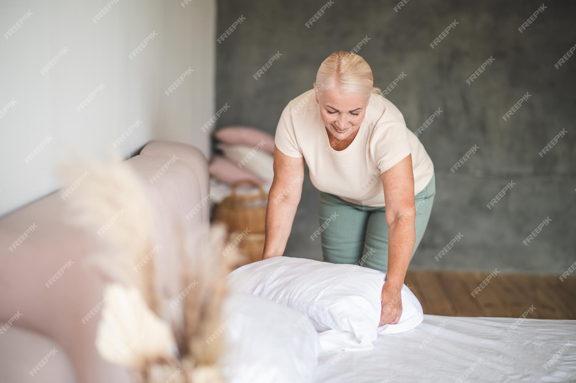 menina bonitinha arrumando a cama arrumando travesseiro e capa de