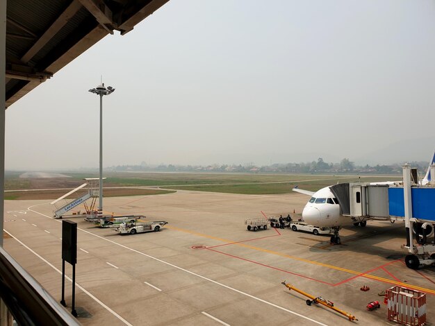 Foto manhã nebulosa em um aeroporto com uma aeronave atracada no equipamento de apoio terrestre do portão