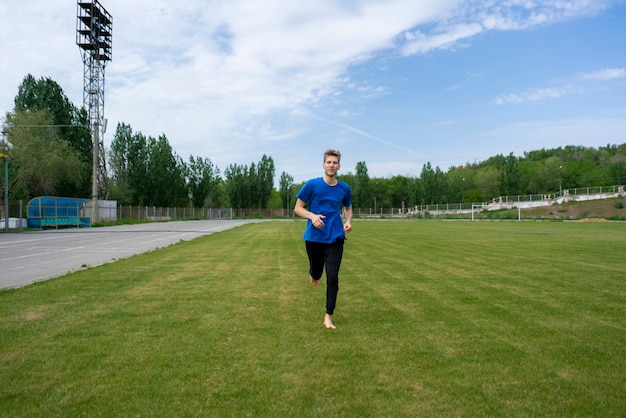 Manhã saudável, atleta masculino correndo em campos de grama verde com os pés descalços