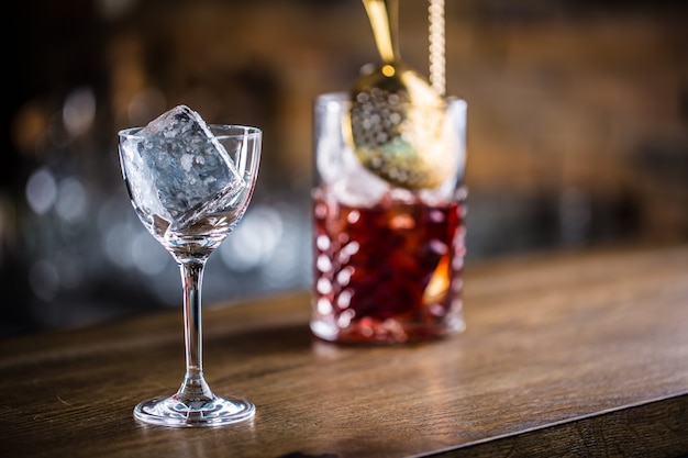 Manhattan-Cocktail-Getränk, das auf der Bartheke in einem Pub oder Restaurant dekoriert ist. Eiswürfel im leeren Glas.