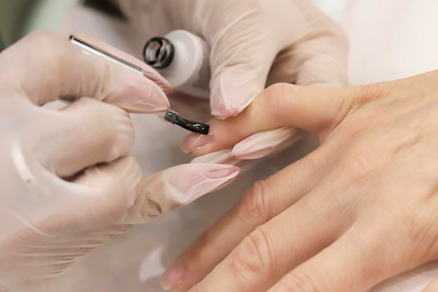 Manicura aplicando esmalte de uñas en las uñas